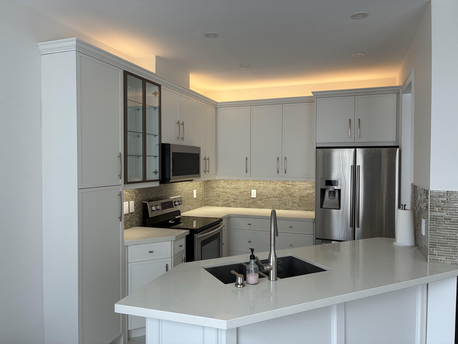 Perimeter cove lighting washing the ceiling of a renovated Toronto kitchen, with under-cabinet lighting on the backsplash below