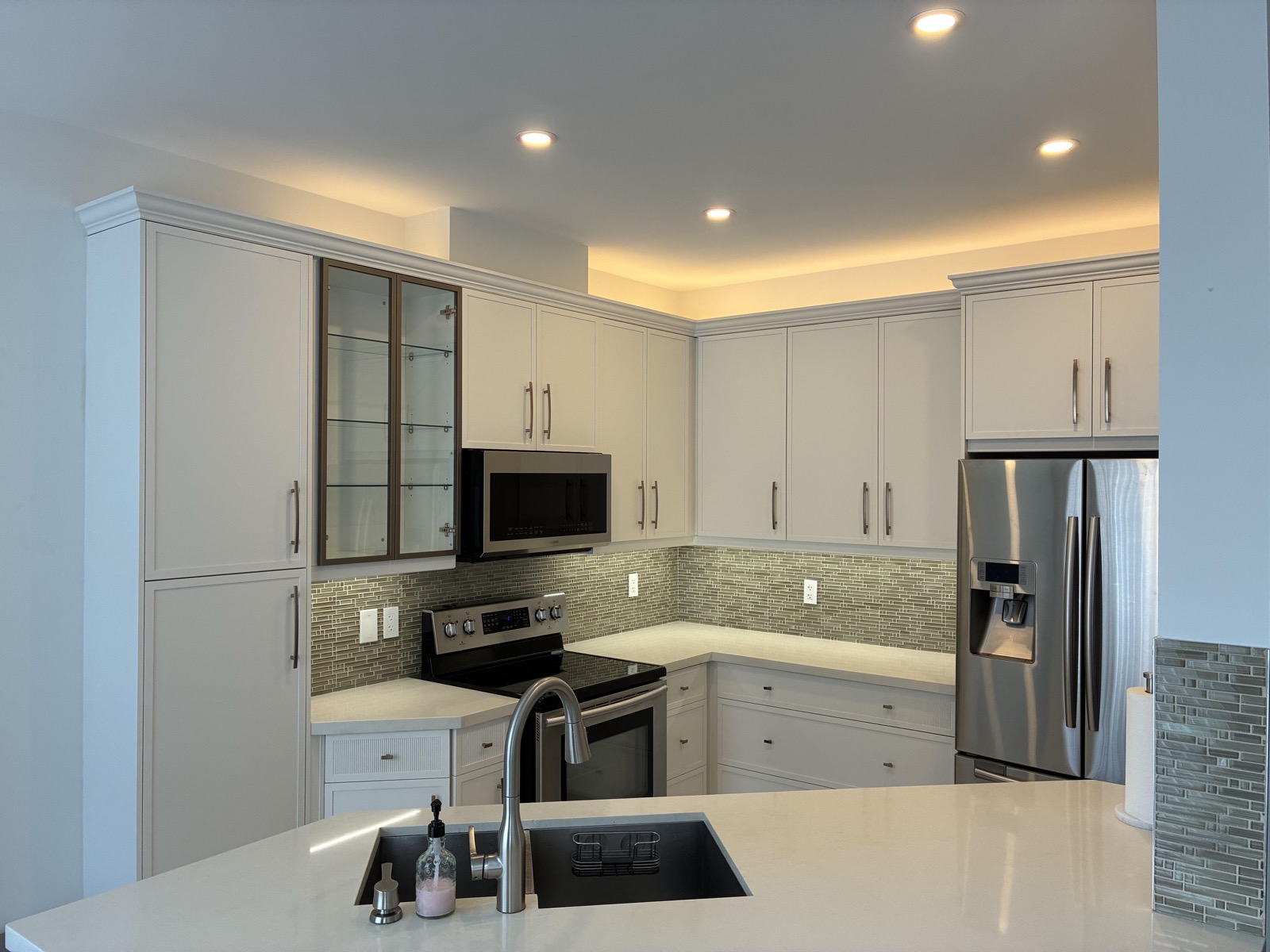 Under-cabinet lighting running the full cabinet length, lighting the countertop and glass tile backsplash evenly with no visible dots