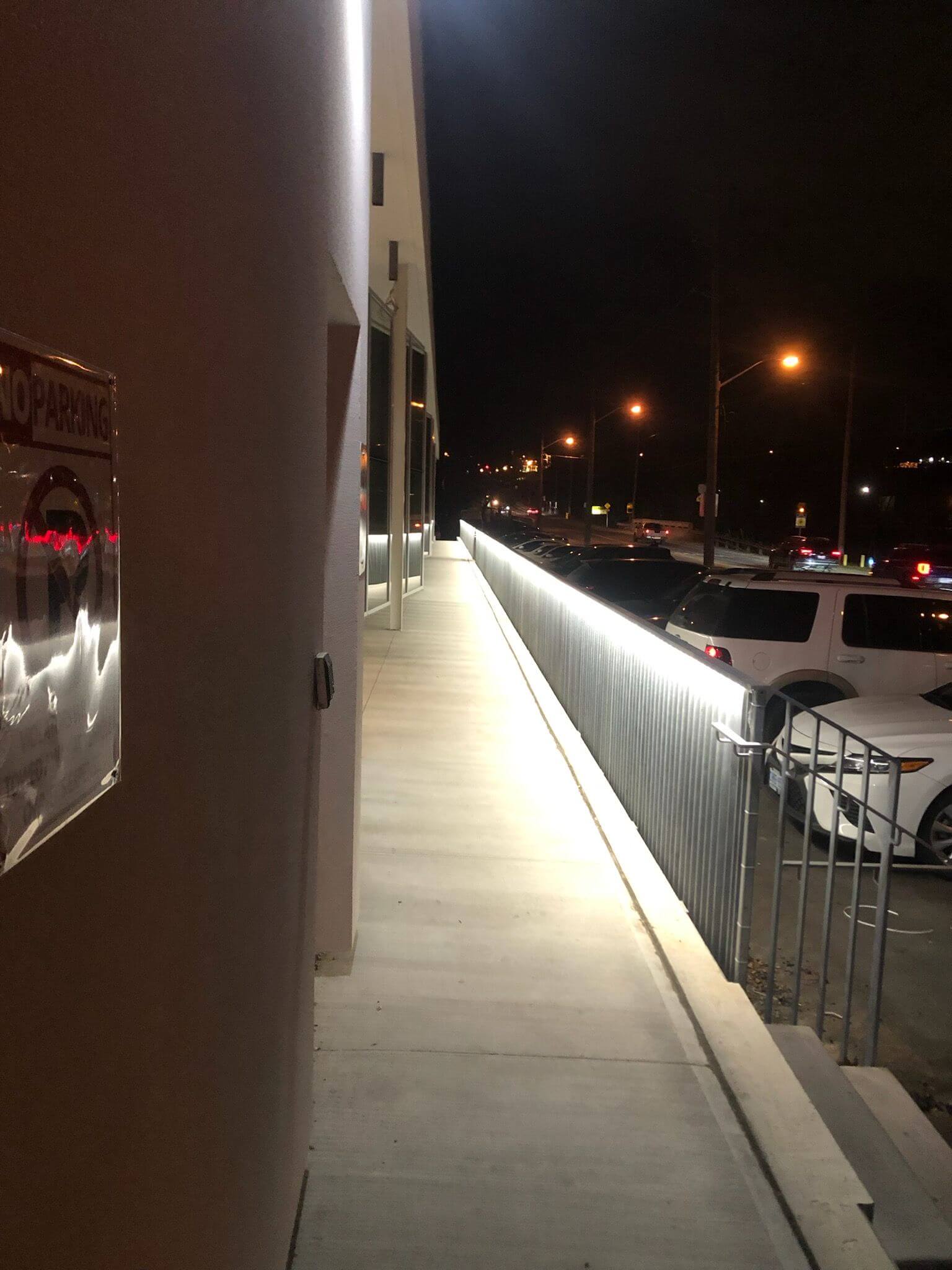 Outdoor elevated walkway illuminated by custom rail lighting at night